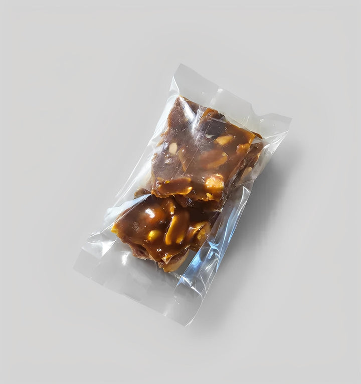 Cannabis brittle pieces in clear pack on plain grey background