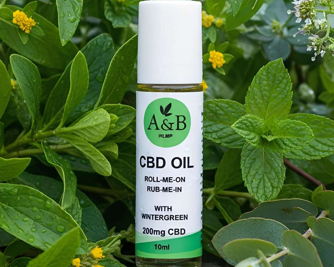 A&B CBD oil roll-on bottle with wintergreen, 200mg CBD, surrounded by fresh green leaves.