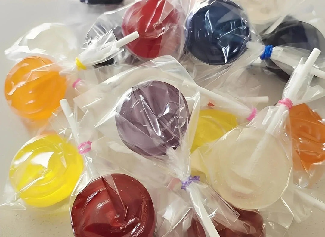 Colorful lollipops in clear plastic bags on a light surface