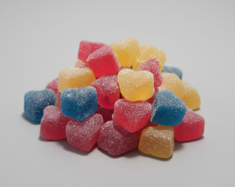Stack of colorful gummy hearts on a white plate with a blurred background