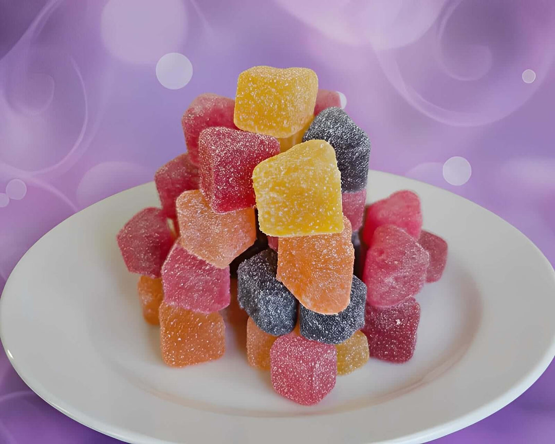Stack of colorful gummy cubes on a white plate with a blurred background