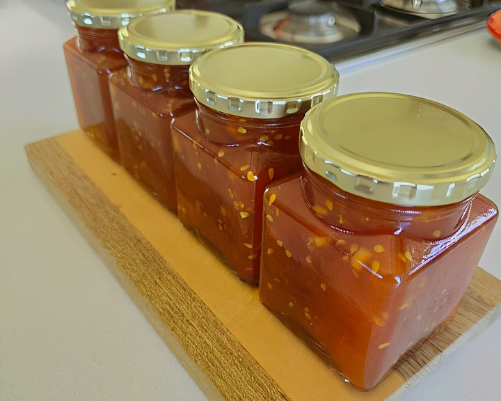 Premium infused fruit jam jars with rich red preserves and gold lids for a gourmet edible experience